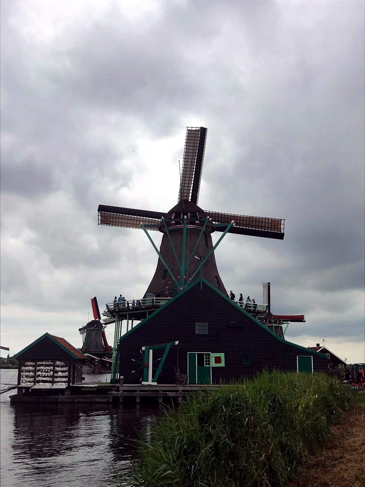 Thatched windmill with open sails beneath dramatic grey clouds