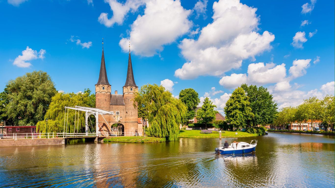 Delft's historic Oostpoort gate beside the canal under a bright blue sky