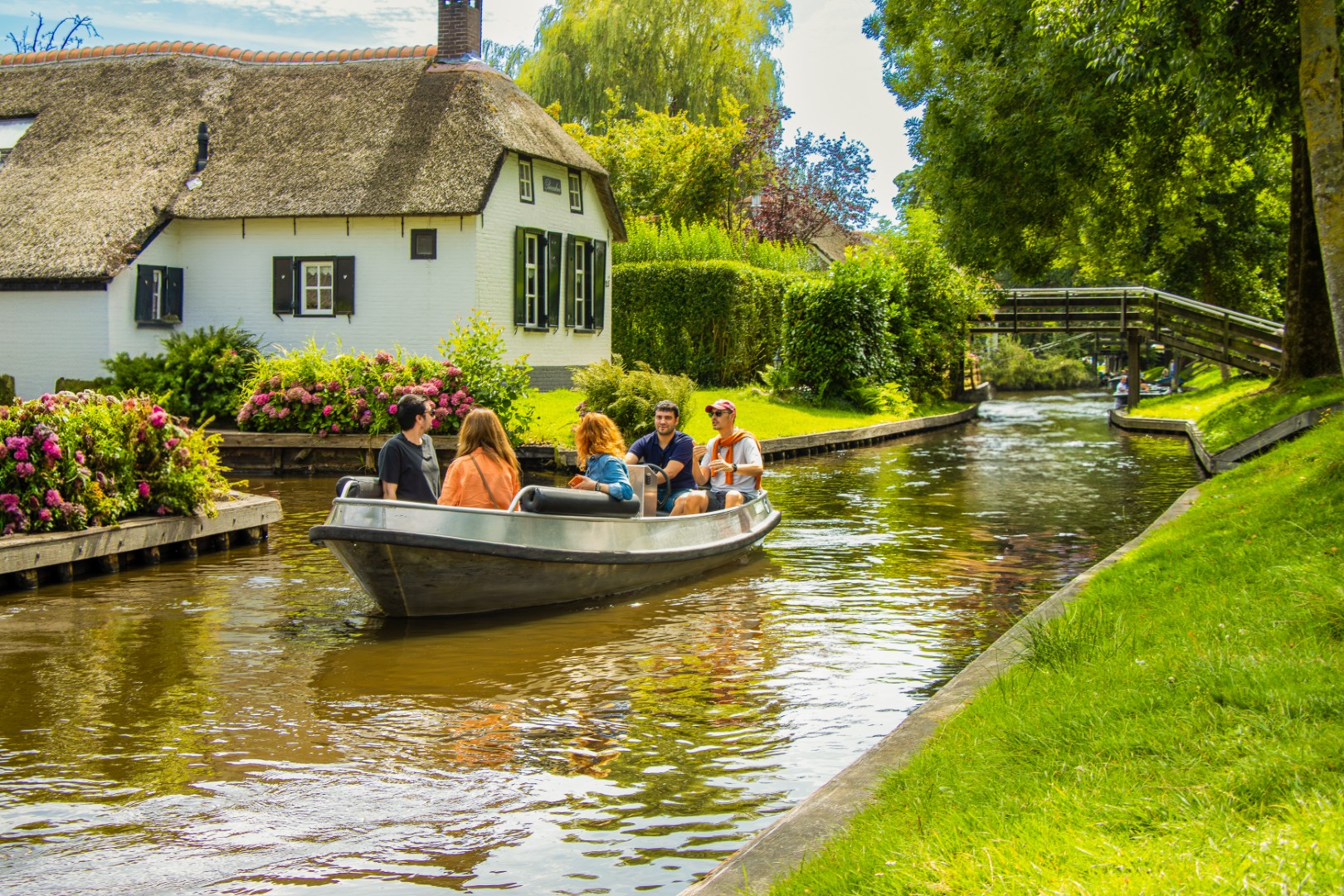 Small boat passing the white thatched Bouchée cottage on a Giethoorn canal