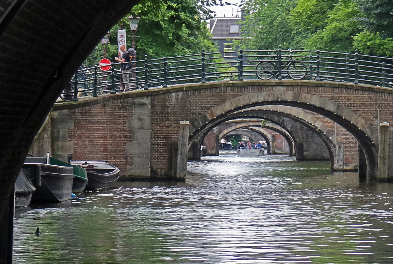 View through a row of arched brick bridges over an Amsterdam canal